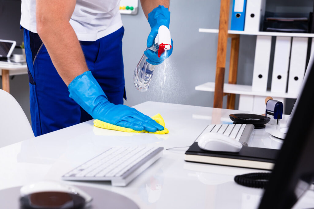 Janitor cleaning white desk in office